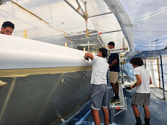 Painters working along the hull side between coats