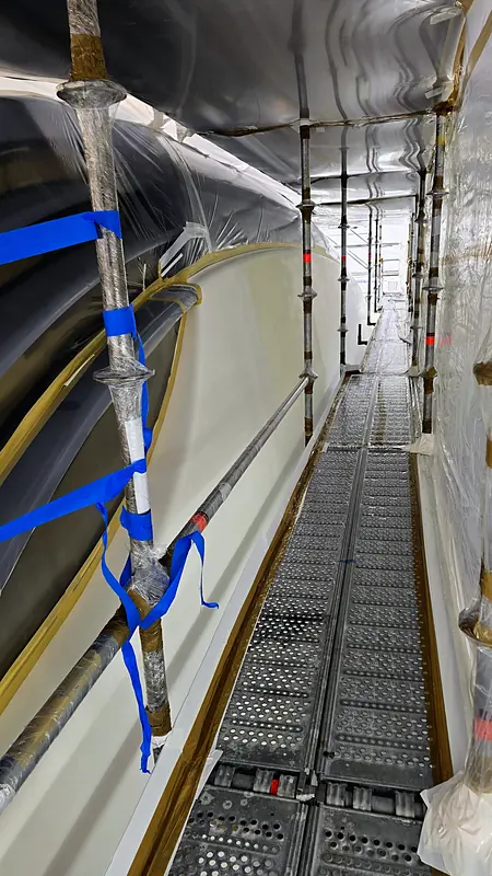 Scaffold walkway along a masked hull under containment